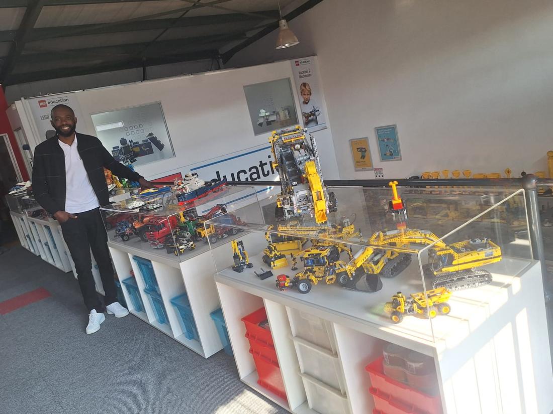 A team member beside display cases of large LEGO Technic machine models at a LEGO Education facility